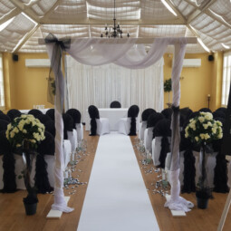 white wooden arch decorated in white chiffon and black bows