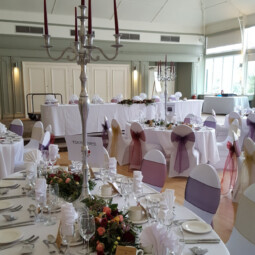 wedding room with plum burgundy and gold sashes and candelabra centerpieces