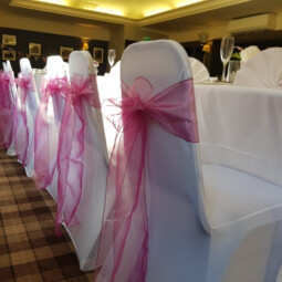 white chair covers with raspberry sashes